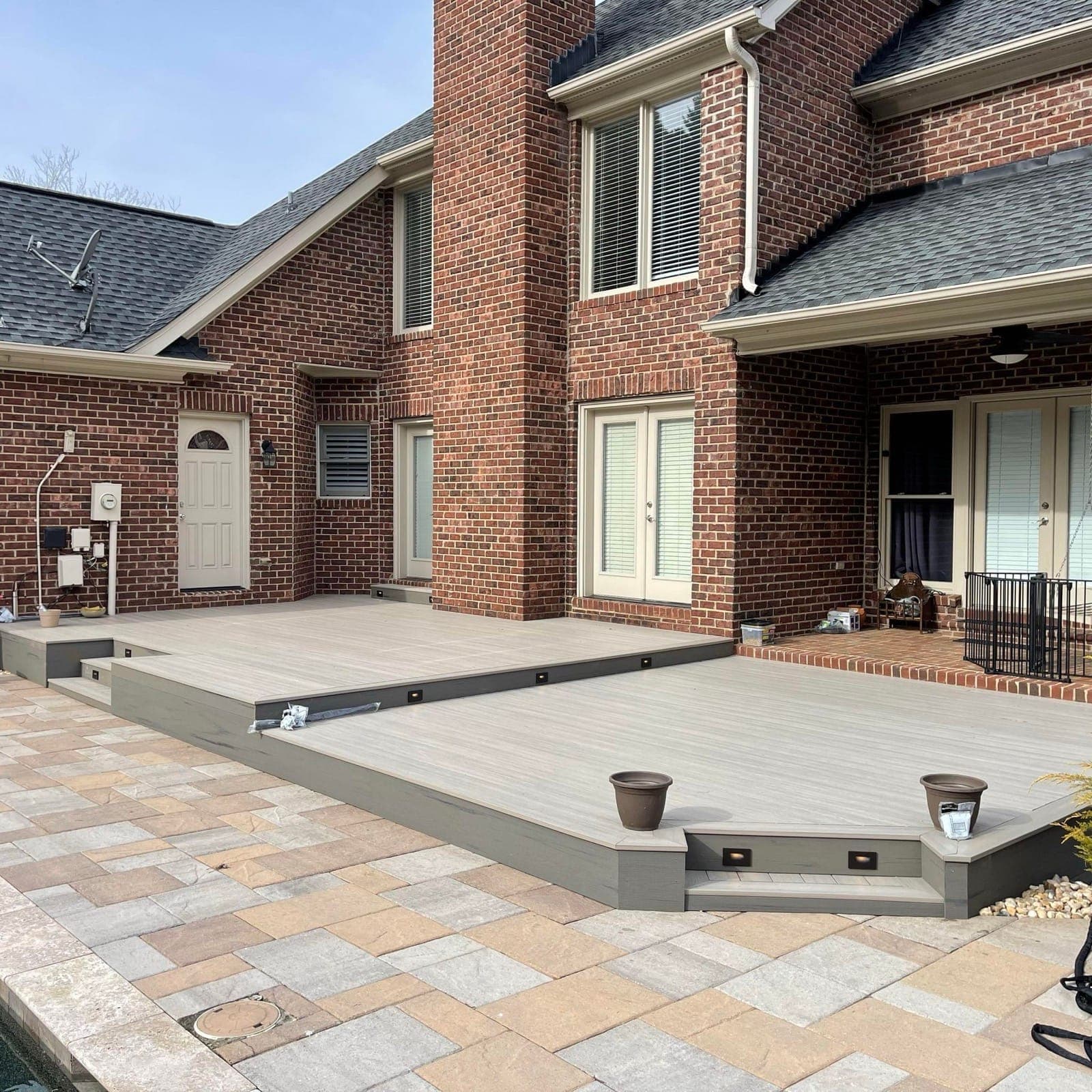 Paver patio with seat-step lighting wrapping a composite deck at a brick home, Charlotte NC